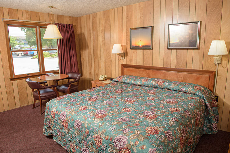 A wide view of a hotel room with a large bed, table, chairs, and window.